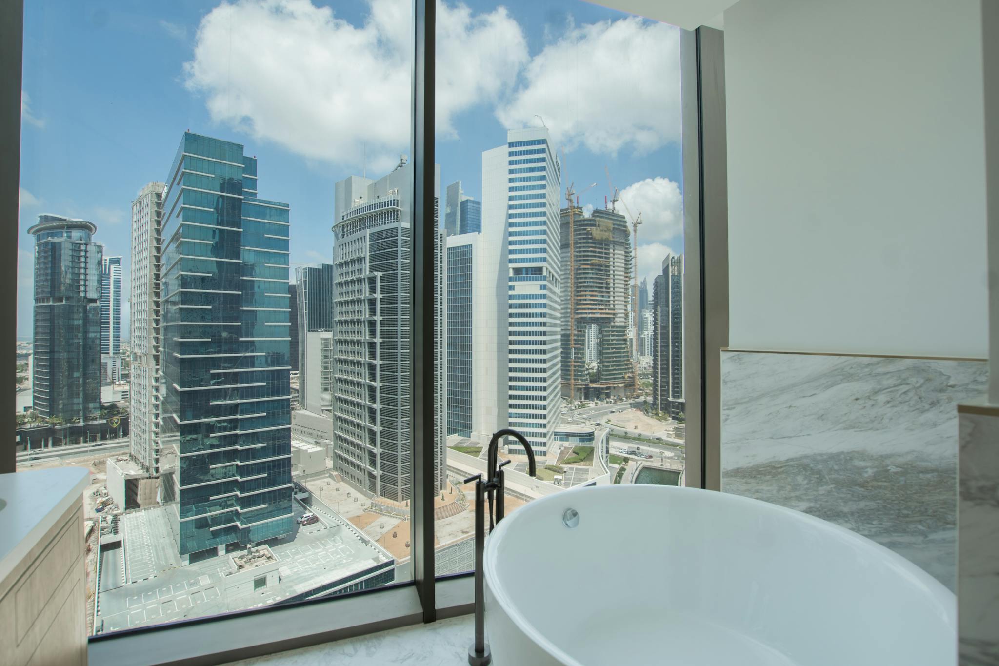 A modern bathtub with a breathtaking view of a vibrant city skyline through large windows.