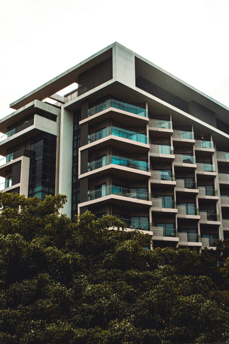 Low angle view of a modern residential building with balconies amidst greenery.